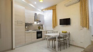 A compact kitchen with a dining area, a built-in oven, and a flat-screen TV mounted on the wall. - Gold Vatican Apartment (Rome)