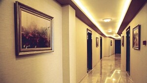 A hotel hallway with a polished floor, framed artwork on the walls, and doors leading to rooms. - Bursa Suites Apart Hotel (Bursa)
