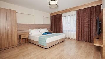 Una habitación de hotel moderna con cama, armario de madera, mesita de noche y televisor.