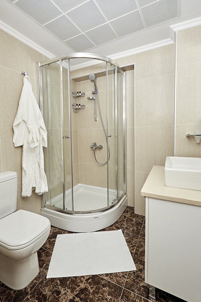 A bathroom with a glass-enclosed shower, a toilet, a sink, and a towel rack.
