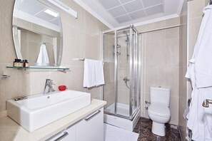 A modern bathroom with a glass-enclosed shower, a white sink, and a toilet. - Bursa Suites Apart Hotel (Bursa)
