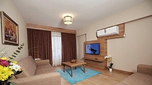 A modern living room with a sofa, a coffee table, a TV, and a plant. - Bursa Suites Apart Hotel (Bursa)