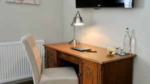 Een houten bureau met een lamp, een stoel, een tablet en een fles.