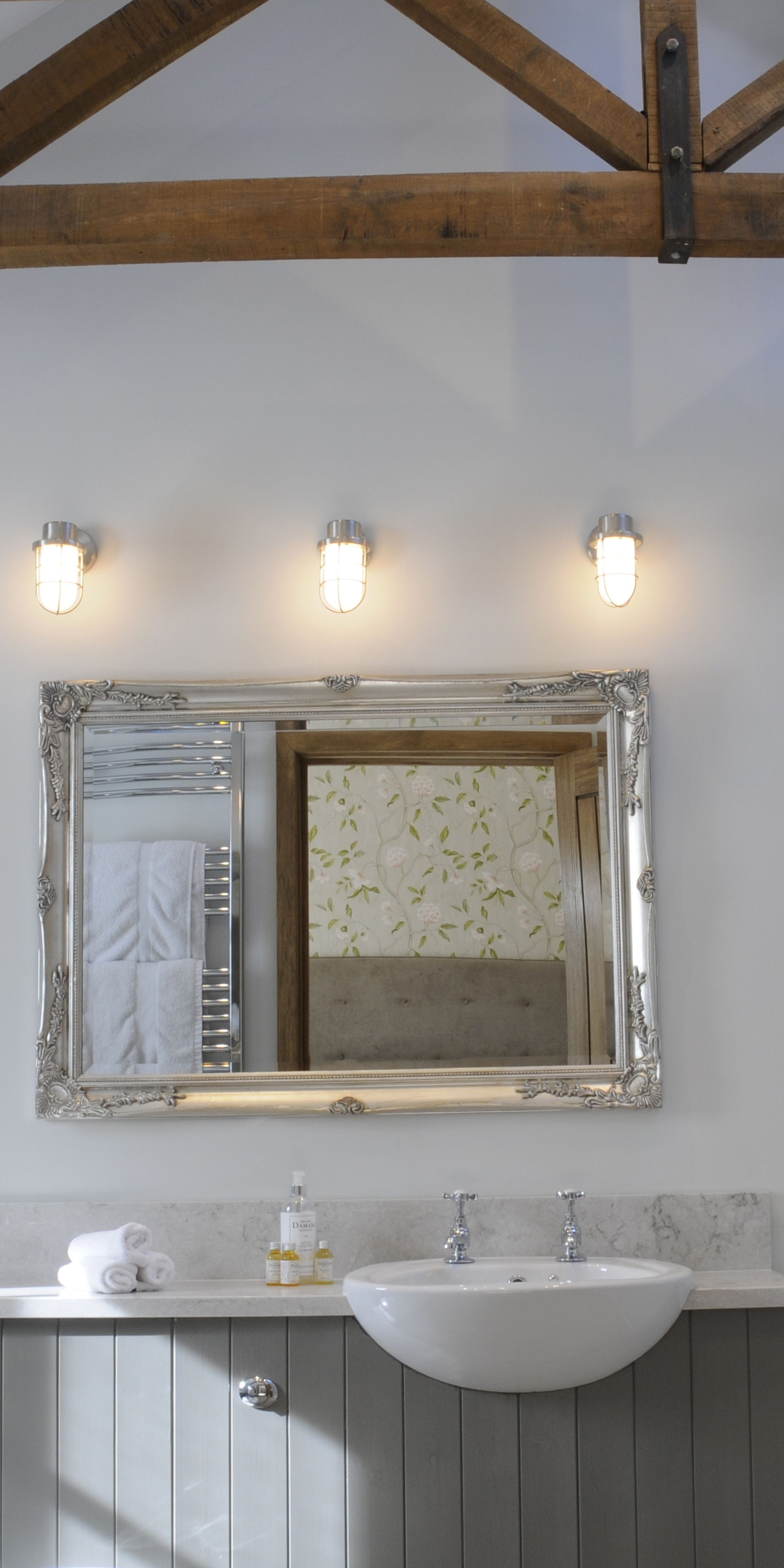 Un baño con un espejo grande, un lavabo y tres luces en la pared.