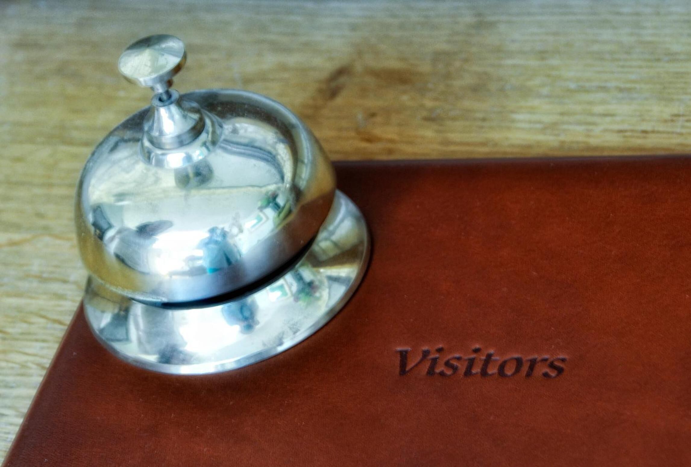 A silver bell with a lid, placed on a brown leather surface.