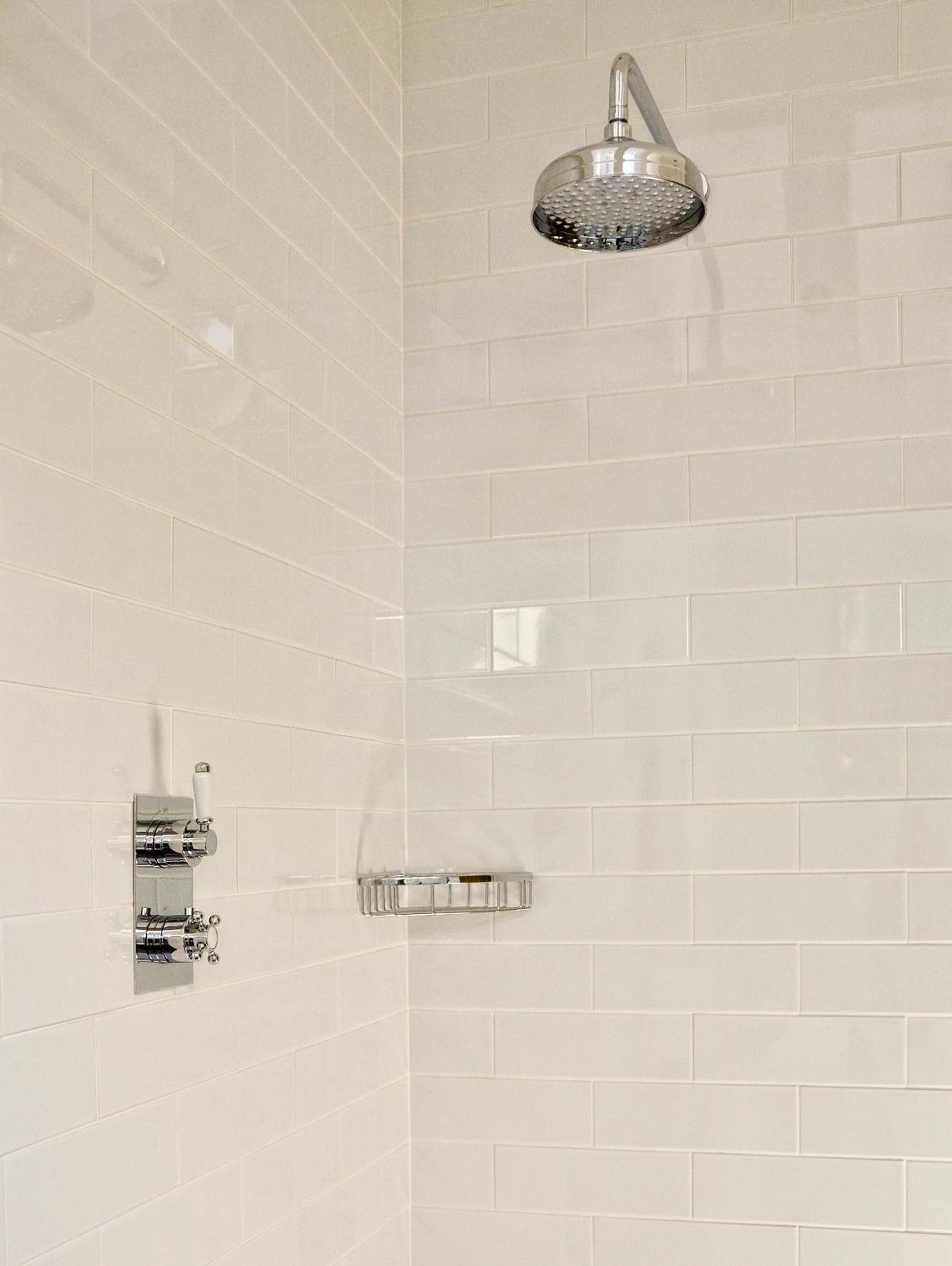 Un espace douche équipé d’un pommeau de douche à main et d’un panneau de commande fixé au mur.