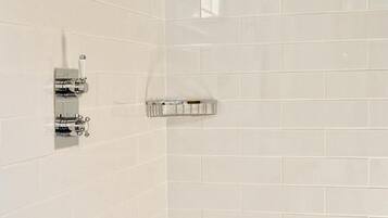 Un espace douche équipé d’un pommeau de douche à main et d’un panneau de commande fixé au mur.