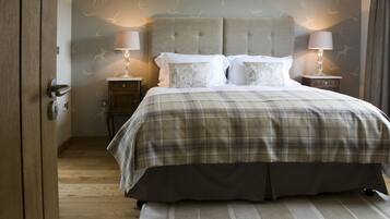 A bedroom with a large bed, two bedside tables, and a wooden door.