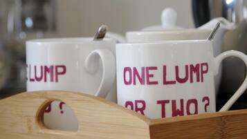 Two white mugs with "ONE LUMP OR TWO?" printed on them, placed on a wooden tray.