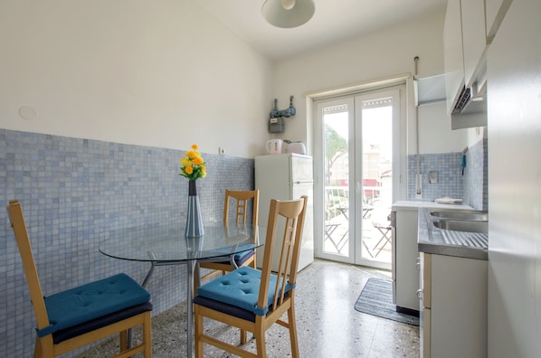 A compact kitchen with a dining table, chairs, and a refrigerator.