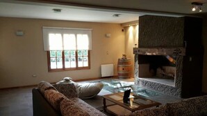 A living room with a sofa, a coffee table, a fireplace, and a window with blinds.