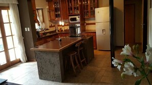 A kitchen with a central island, wooden cabinets, a microwave, and a refrigerator.