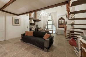A spacious living area with a sofa, a dining table, and a kitchen in the background. - Poliziano Colosseum Apartment (Rome)