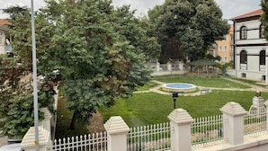 A courtyard with a fountain, surrounded by a white fence and trees. - Limon Pansiyon  (Edirne)