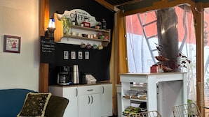 A cozy living room with a coffee-themed decor, including a sign that reads "Premium Quality Coffee," a coffee machine, and a shelf with various coffee cups and mugs. - Limon Pansiyon  (Edirne)