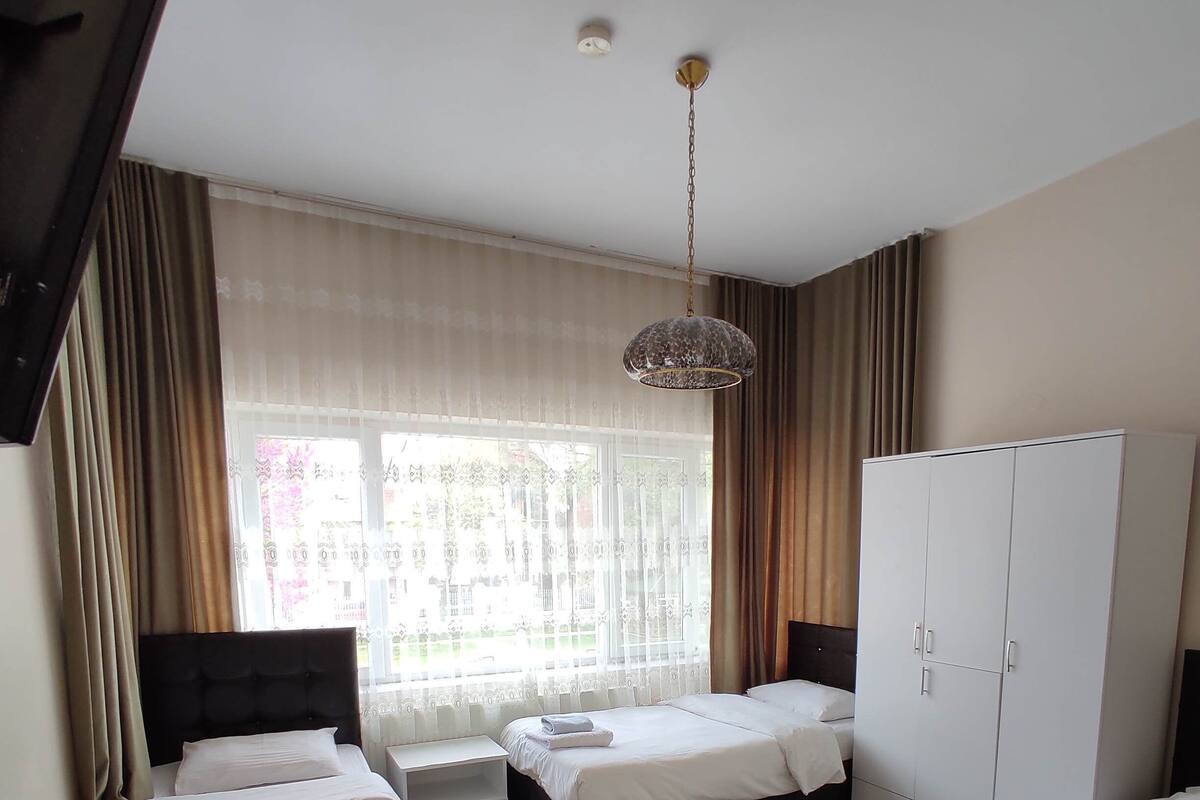 Habitación de hotel con dos camas, un armario, un escritorio y un ventanal con cortinas.