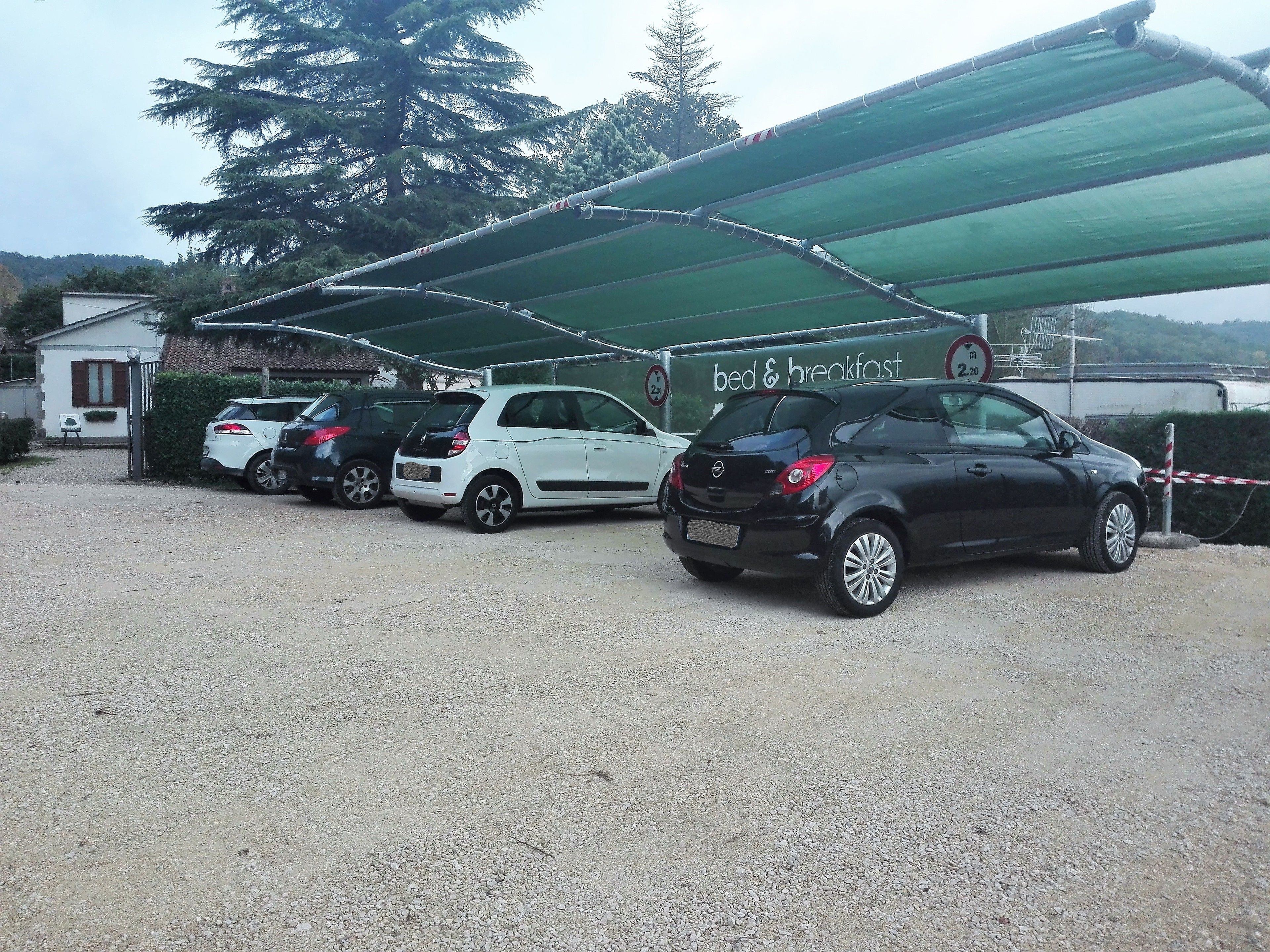 Un área de estacionamiento con coches, un refugio cubierto y un cartel que indica 'bed & breakfast'.