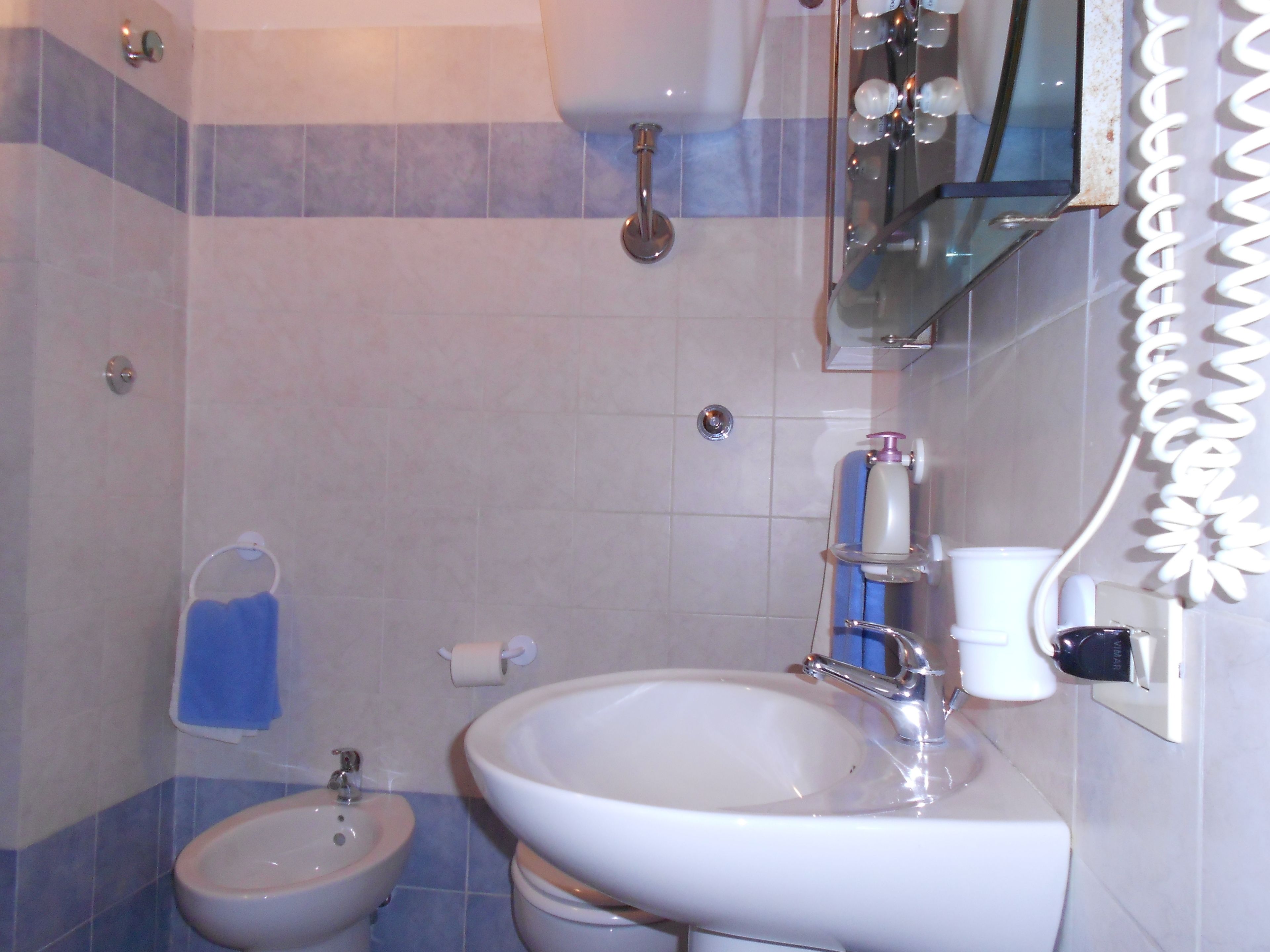 Un baño con bidé, lavamanos y espejo.