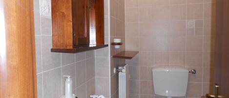 Un baño con un mueble de madera, un lavamanos, un inodoro y un perchero para toallas.