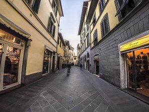 A narrow street lined with shops and buildings, featuring a variety of storefronts and architectural styles. - Ariento House (Florence)