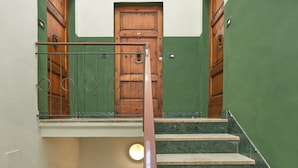 A staircase with green walls and wooden doors, leading to an upper floor. - Ariento House (Florence)