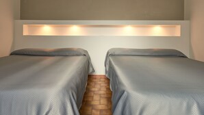 A room with two beds, a brick floor, and a wall-mounted light fixture. - Ariento House (Florence)