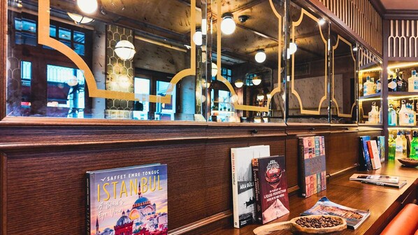 Un área de bar con mostrador de madera, libros y una taza de café.