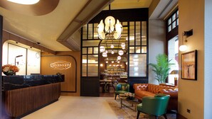A hotel reception area with a black marble counter, a reception desk, a seating area with a sofa and chairs, a bar, and a chandelier. - Momento Golden Horn Hotel (Istanbul)