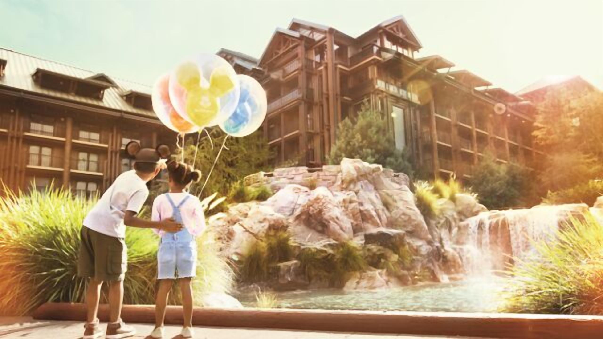 Un bâtiment de style architectural traditionnel, agrémenté d’un élément aquatique et sur lequel on aperçoit une personne tenant des ballons.
