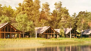 A row of wooden cabins with large windows, surrounded by tall trees and a body of water. - Copper Creek Villas & Cabins at Disney's Wilderness Lodge (Lake Buena Vista)