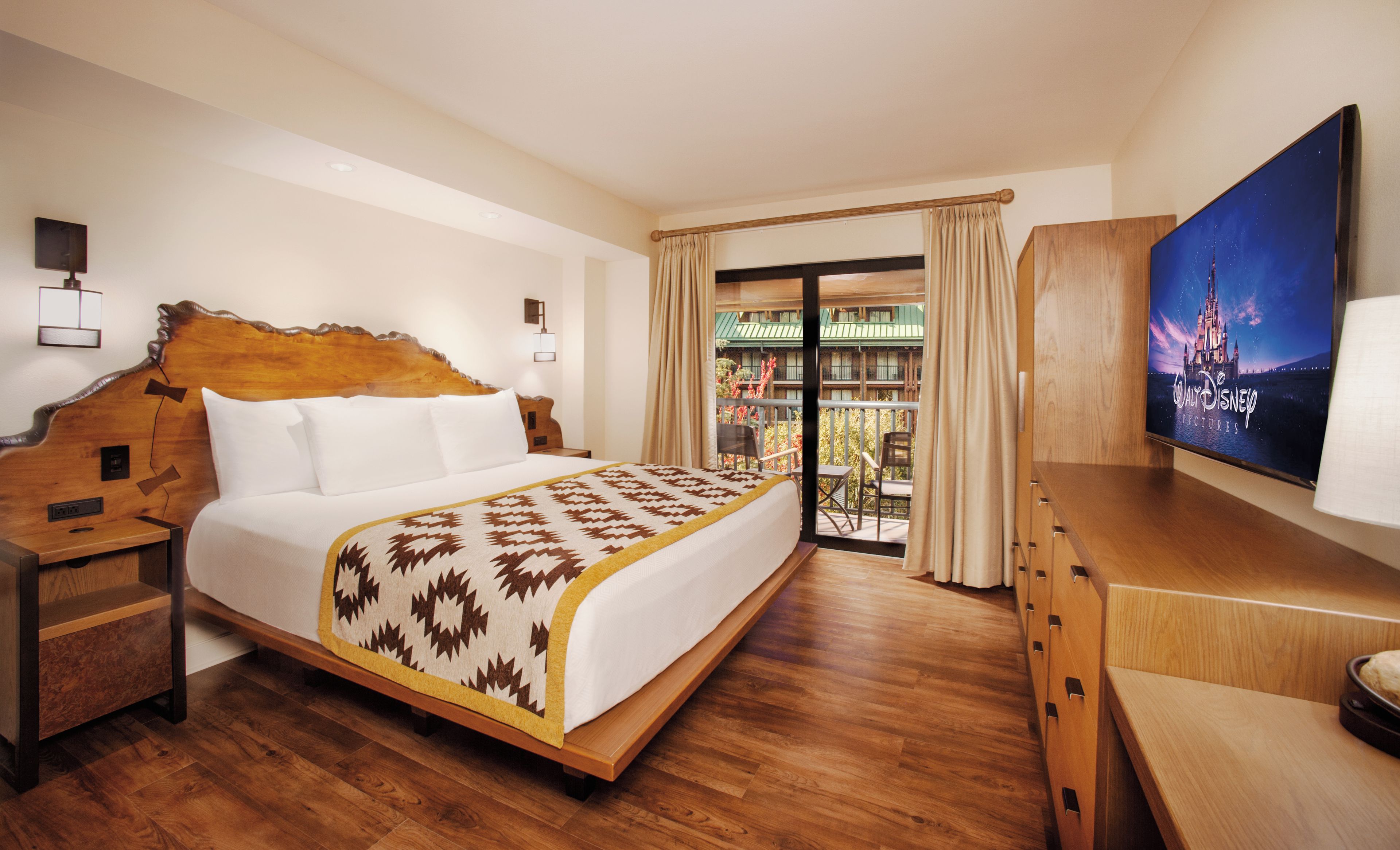 Een hotelkamer met een groot bed, een houten hoofdeinde, een flatscreen-televisie en een balkon met uitzicht op een gebouw.
