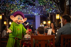 A person in a costume at a dining table with a child and adults. - Copper Creek Villas & Cabins at Disney's Wilderness Lodge (Lake Buena Vista)