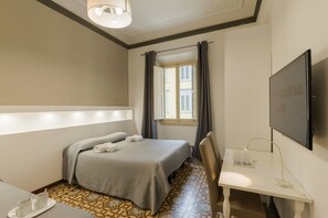 A hotel room with a bed, a desk, a chair, a TV, and a window with curtains. - Residenza San Lorenzo (Florence)