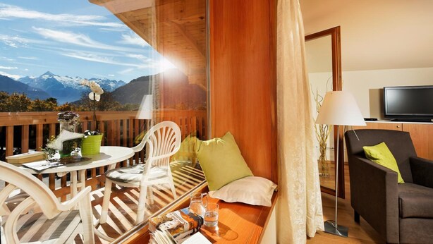 Une pièce confortable avec une terrasse en bois, une table avec des chaises, un canapé, une télévision et une vue sur les montagnes.