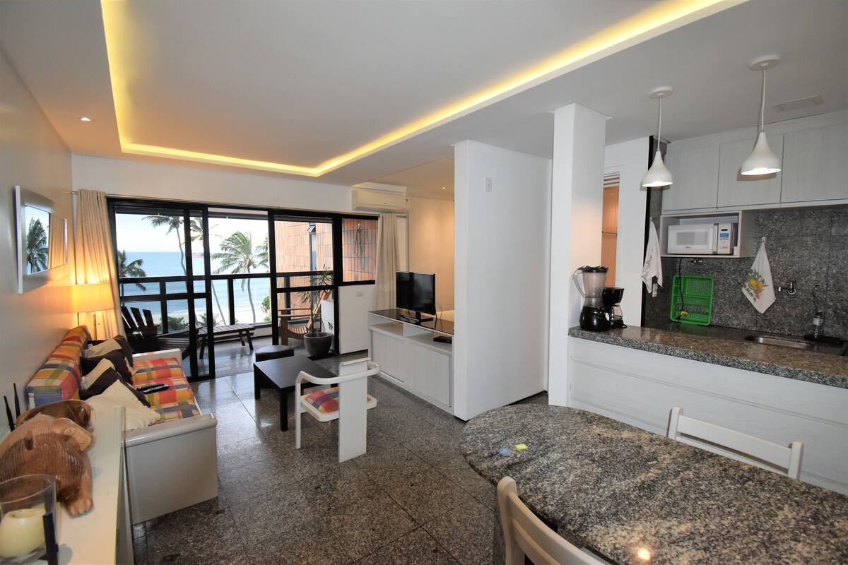 Una habitación de hotel moderna con balcón, zona de comedor y cocina.