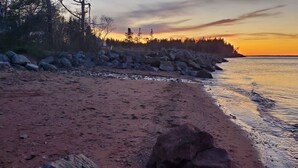 A beach with a rocky shoreline and a forest in the background. - Amherst Shore Country Inn (Lorneville)