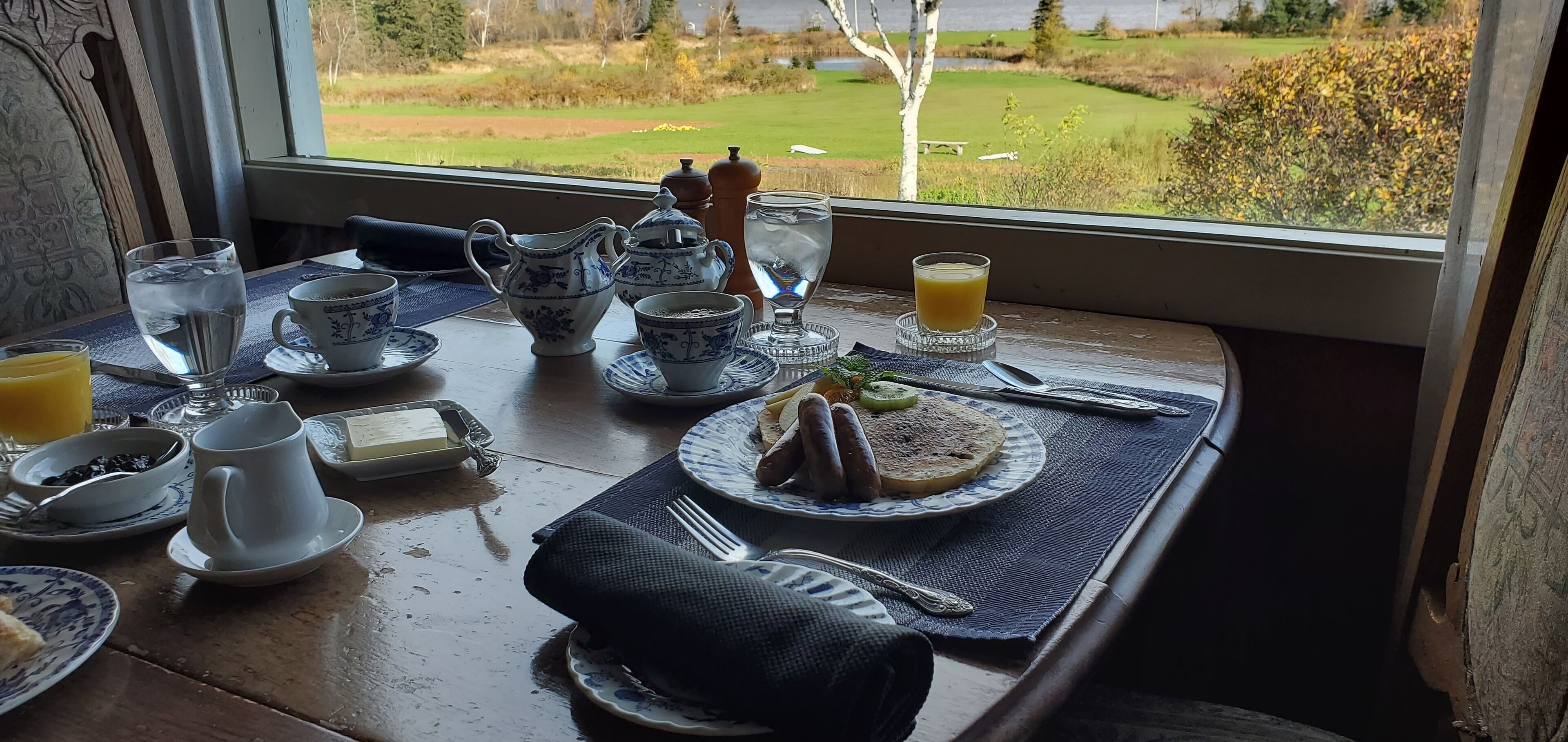 A breakfast table with tea cups, a jug, and a plate with food and drinks.