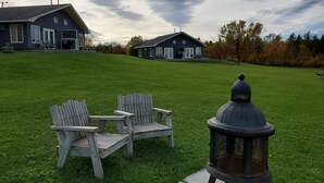 A grassy lawn with two Adirondack chairs and a lantern. - Amherst Shore Country Inn (Lorneville)