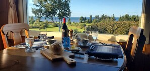 Une table mise pour un repas, avec une bouteille de vin, des verres, un petit pain et des couverts.