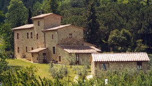 A stone building with multiple rooms, surrounded by lush greenery and trees. - Frateria Di San Benedetto (Montepulciano)