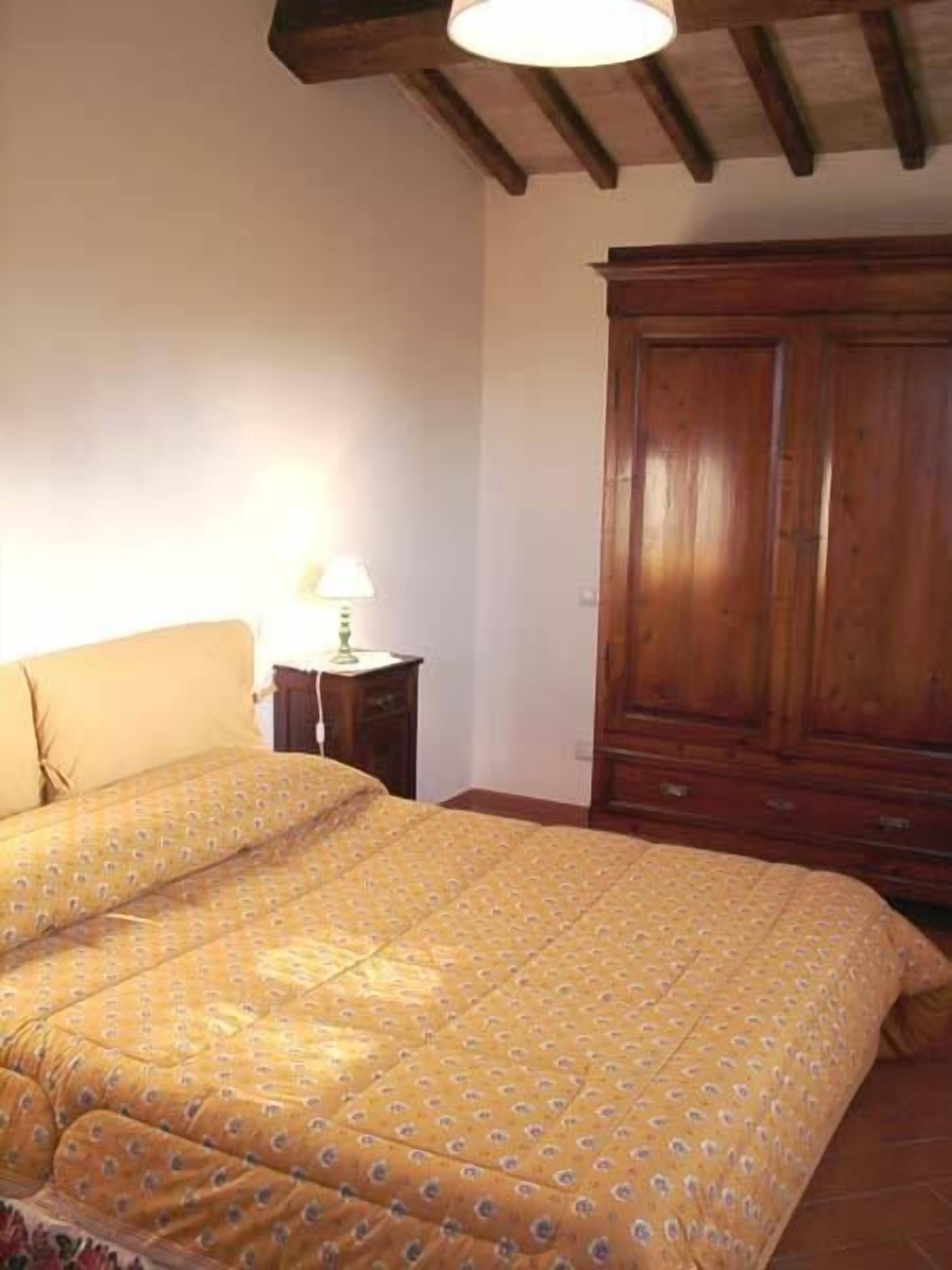 Un dormitorio con una cama, un armario de madera y una mesita de noche con lámpara.