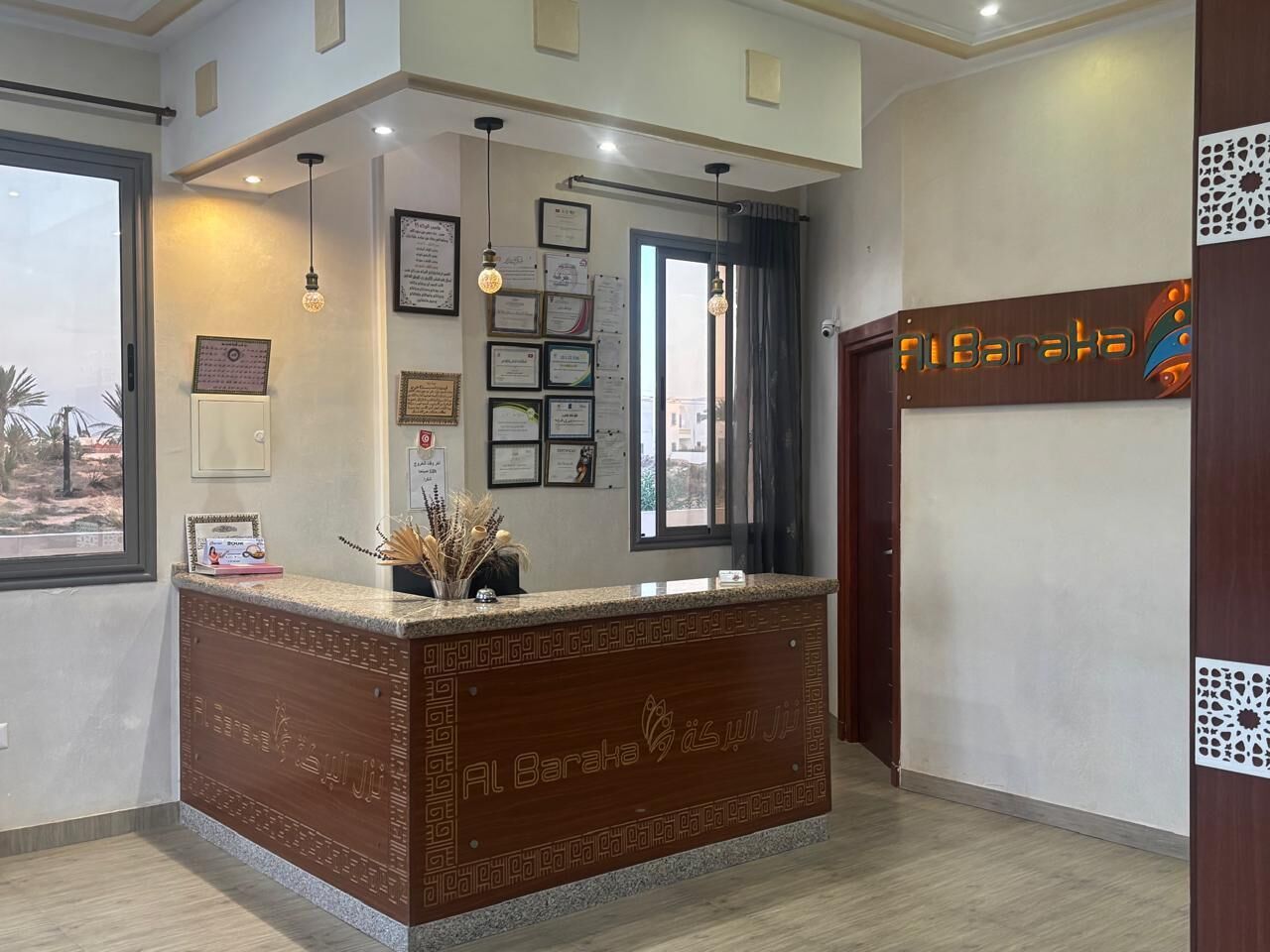 A reception area with a wooden reception desk, framed certificates, and a modern light fixture.