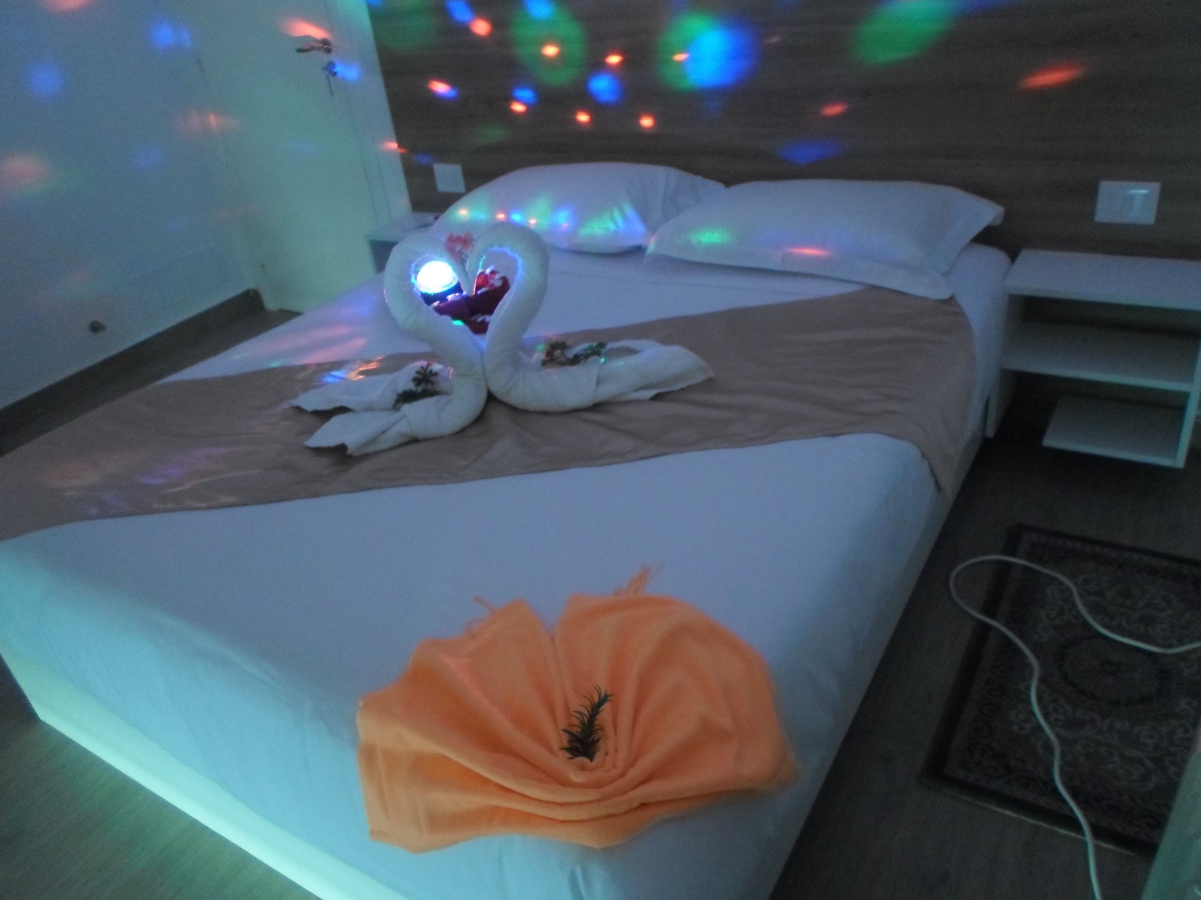 Une chambre d’hôtel avec un lit, des oreillers, un cygne décoratif et un arrangement floral.