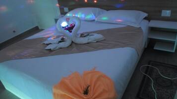Une chambre d’hôtel avec un lit, des oreillers, un cygne décoratif et un arrangement floral.