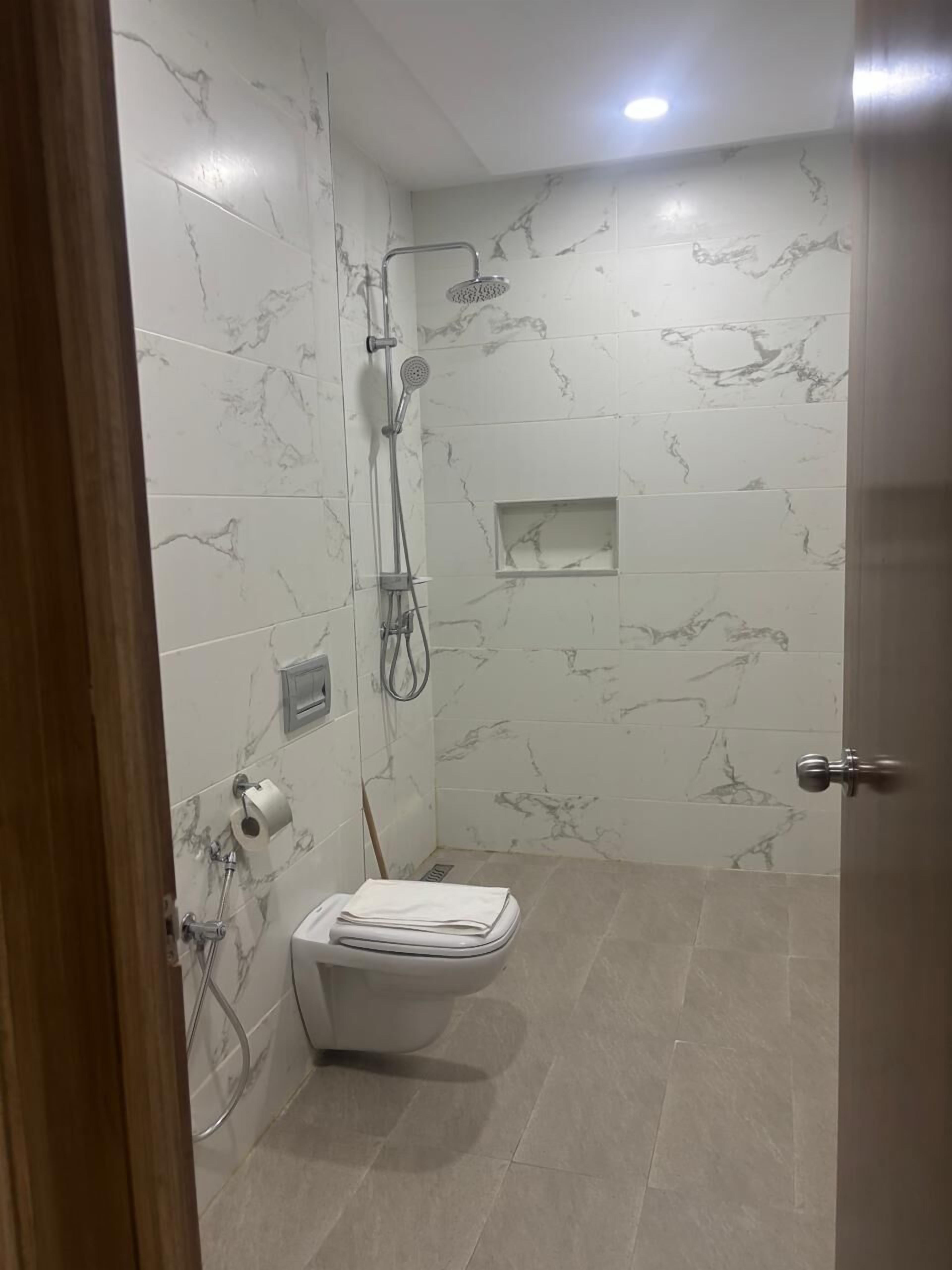 Une salle de bain avec douche, toilettes et murs en marbre.