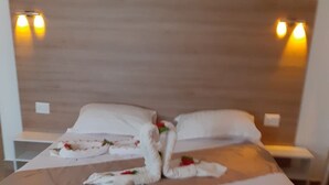 A neatly made bed with white linens, a wooden headboard, and two bedside tables with lamps. - Hôtel Al Baraka (Fatou)