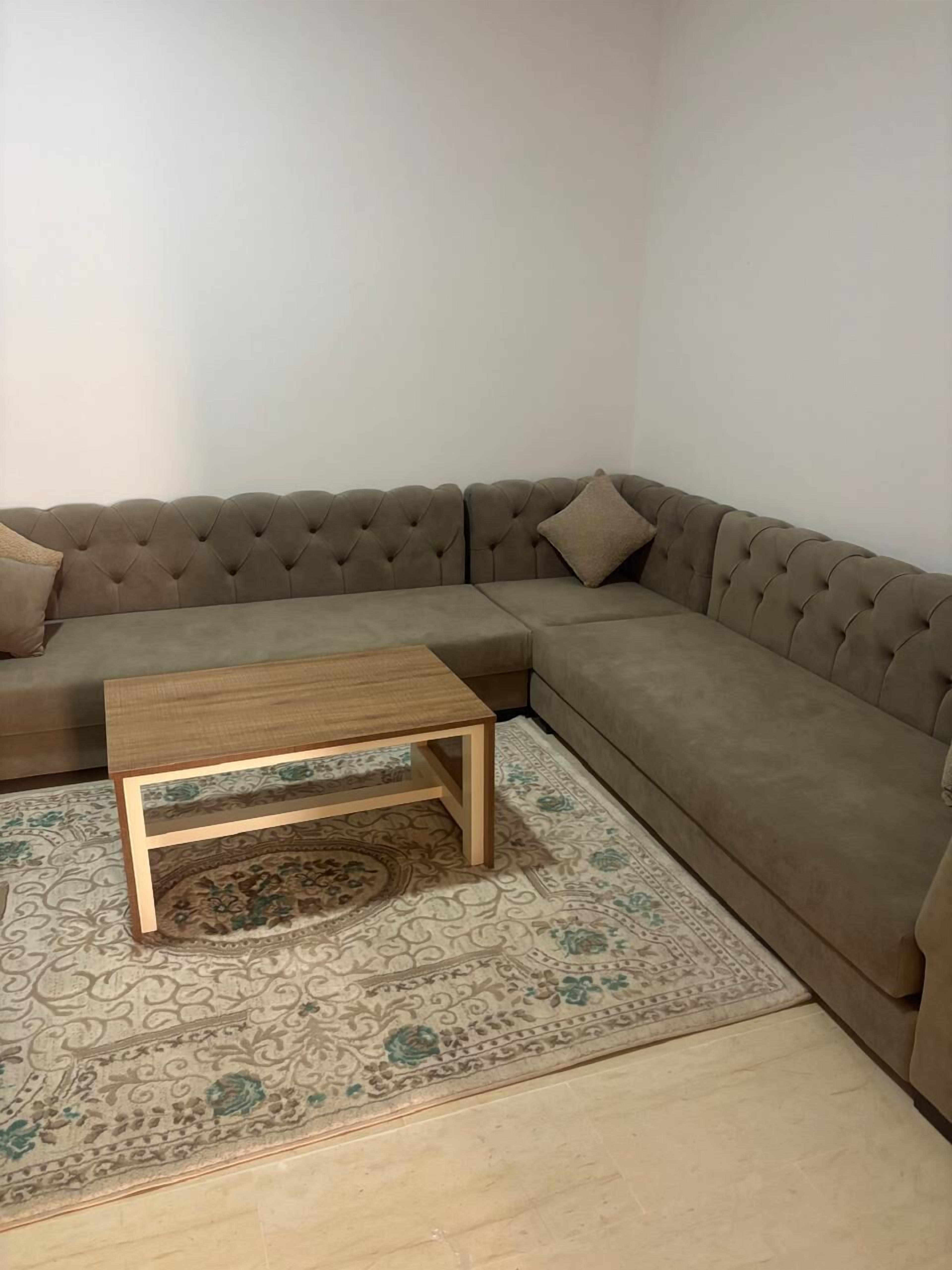 Een hoekzitkamer met een modulaire bank, een houten salontafel en kamerbreed tapijt.