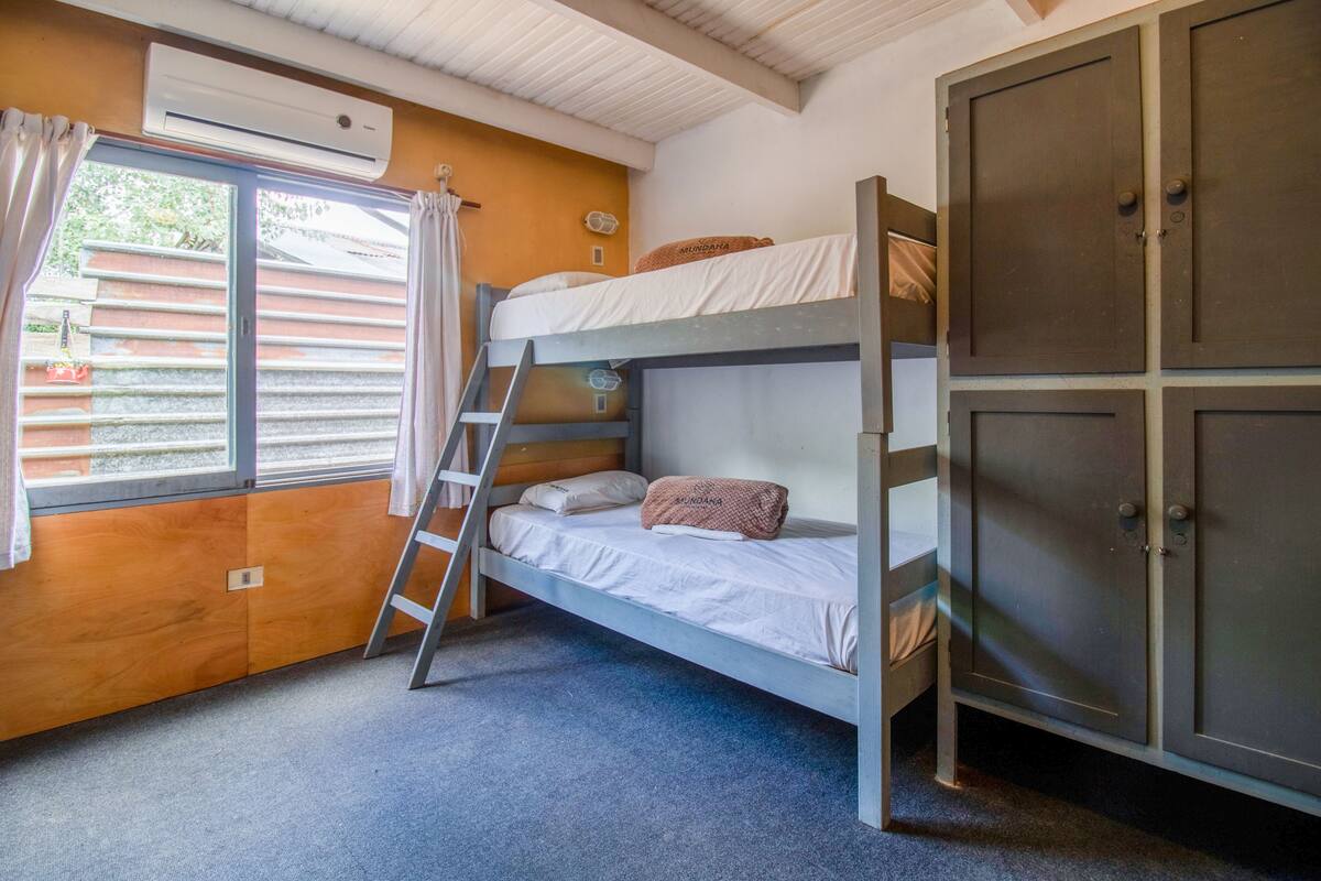 Camera con letto a castello, una scaletta, un armadio e un condizionatore.