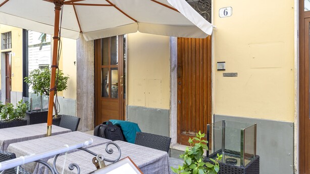 An outdoor seating area with tables, chairs, and a large umbrella. - Zannoni Apartments (Florence)