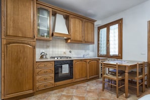 A kitchen with wooden cabinets, a stove, and a dining table with chairs. - Zannoni Apartments (Florence)